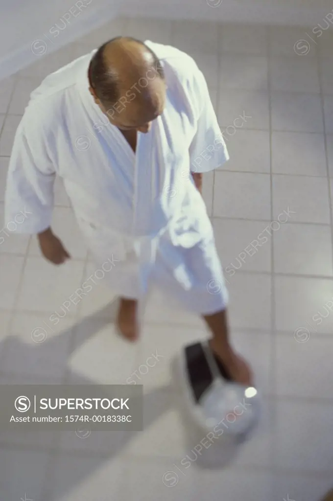 High angle view of a senior man measuring his weight in the bathroom