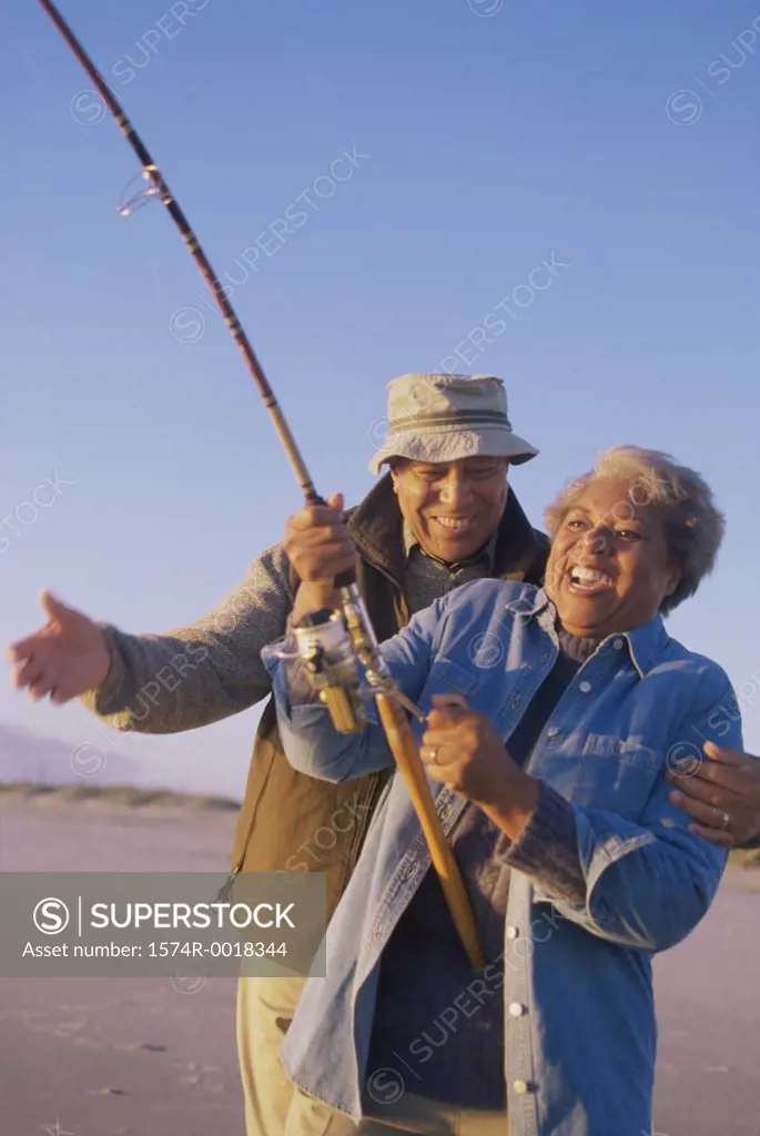 Senior woman holding a fishing rod with a senior man standing beside her
