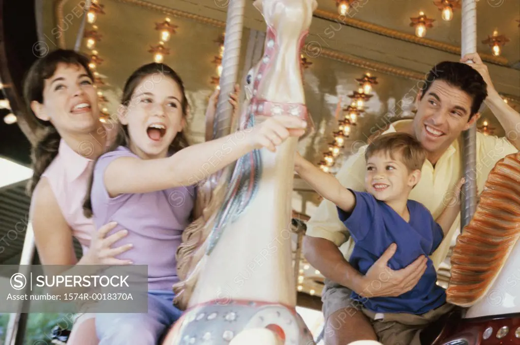 Low angle view of parents with their son and daughter riding on carousel horses