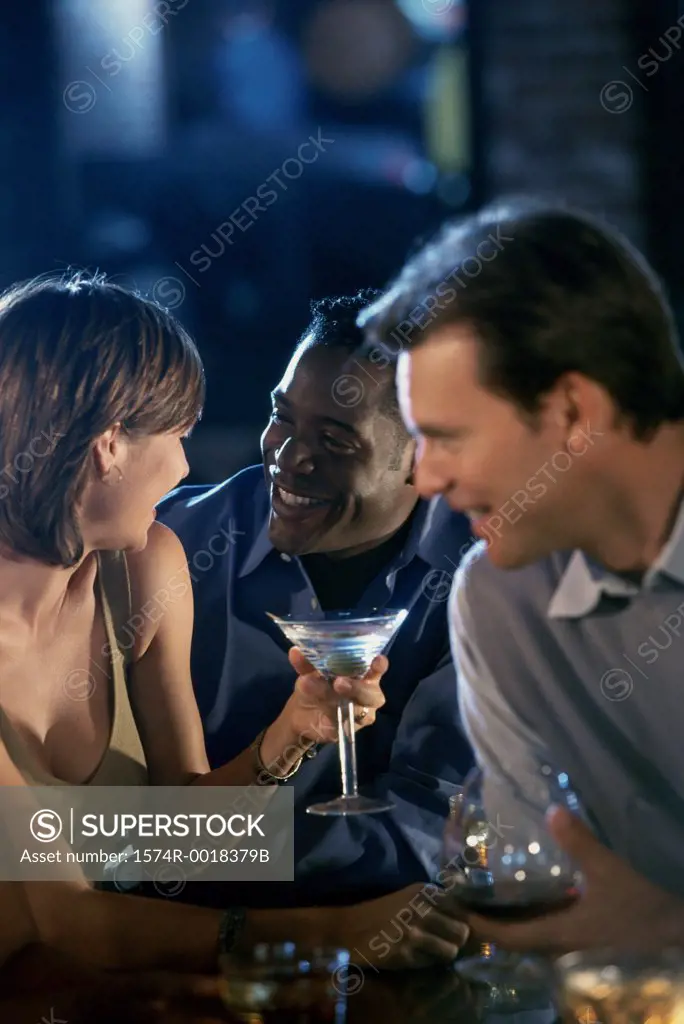 Two young men and a young woman at a bar counter