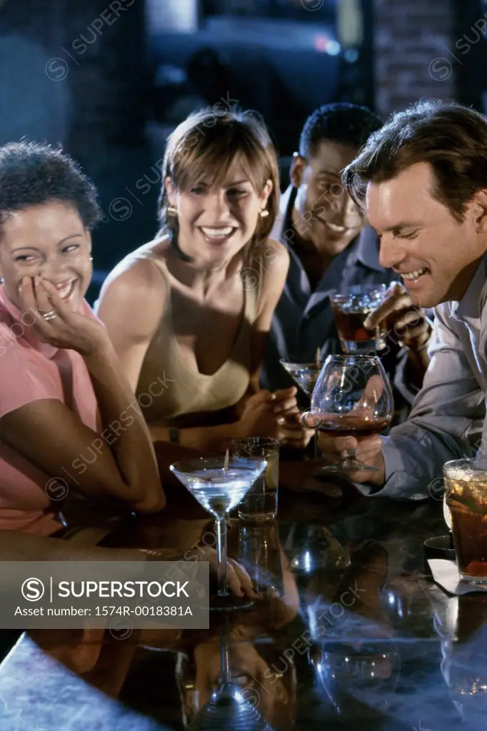 Two young couples in a bar smiling