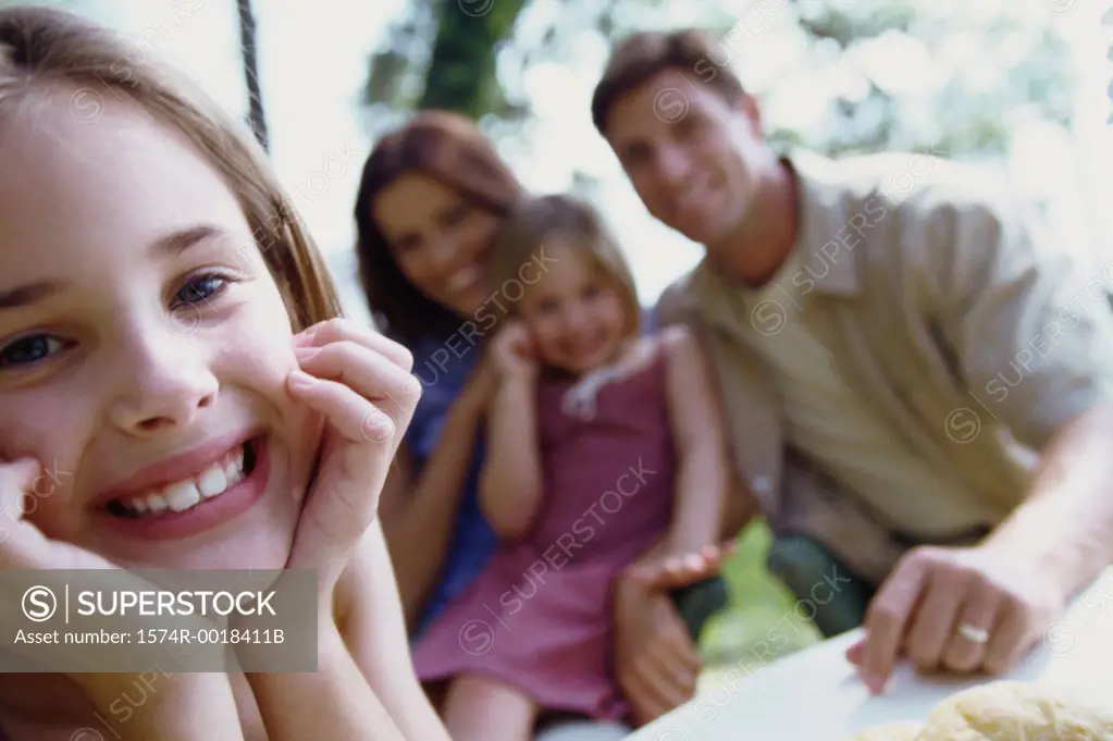 Portrait of a girl smiling with her parents and sister sitting behind her