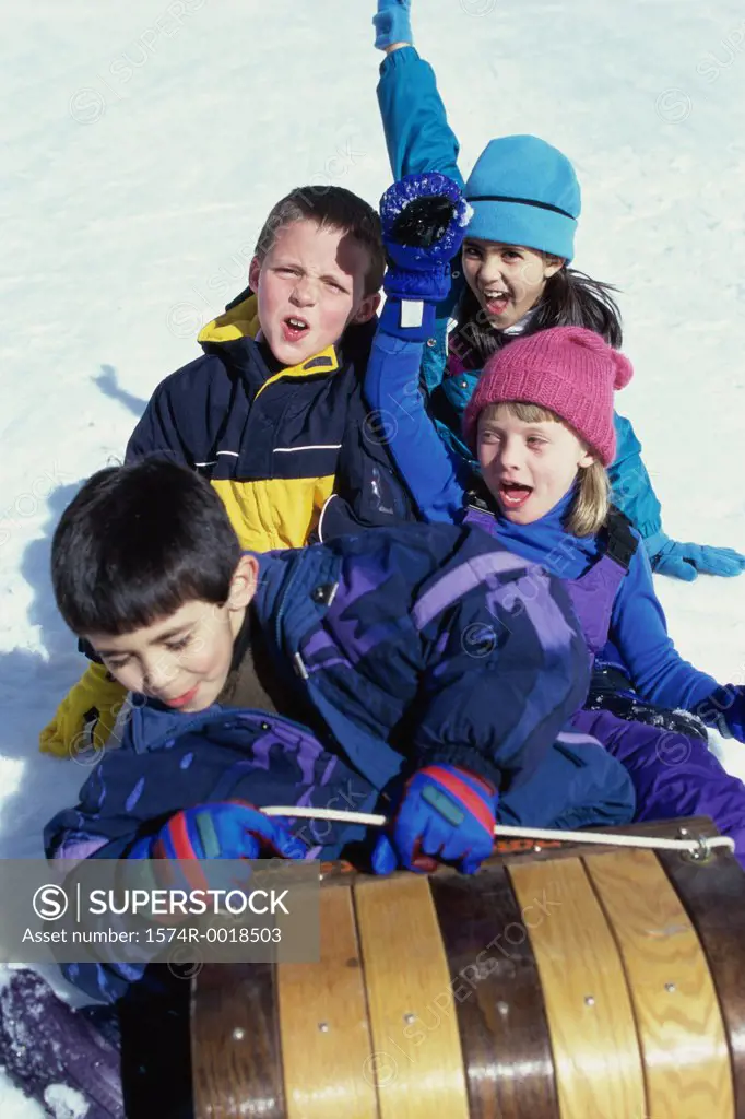 High angle view of two boys and two girls riding on a sled