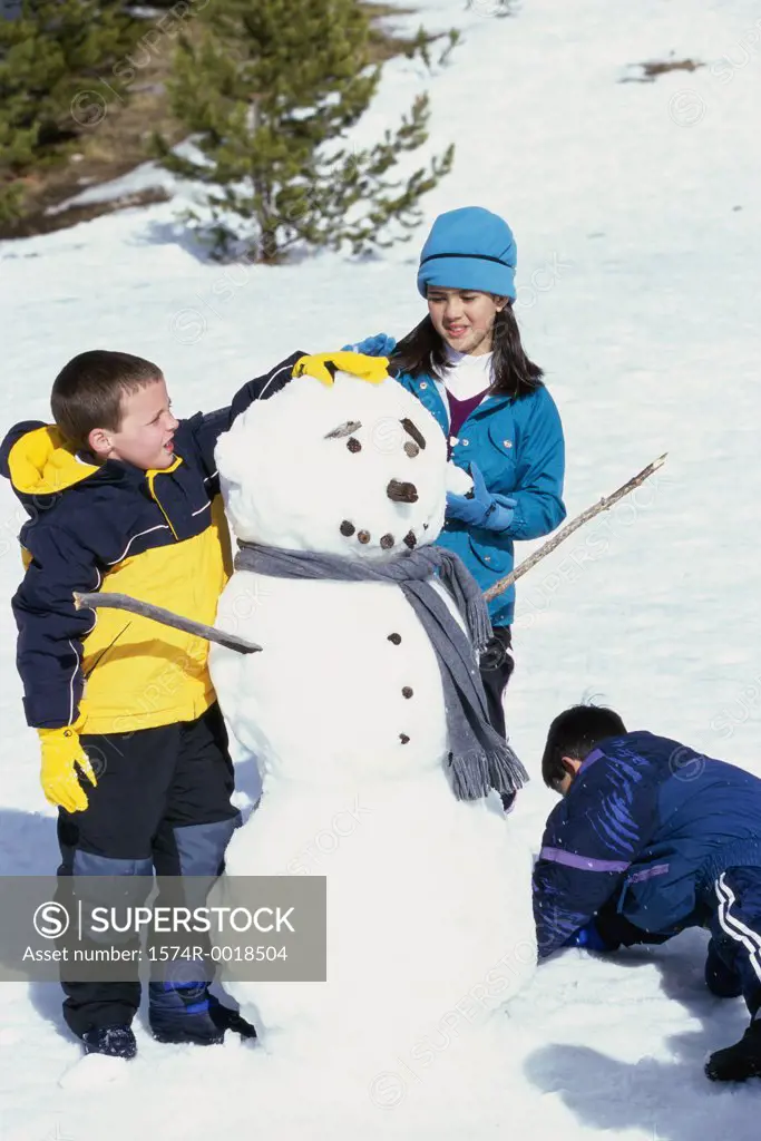 Two boys and a girl making a snowman