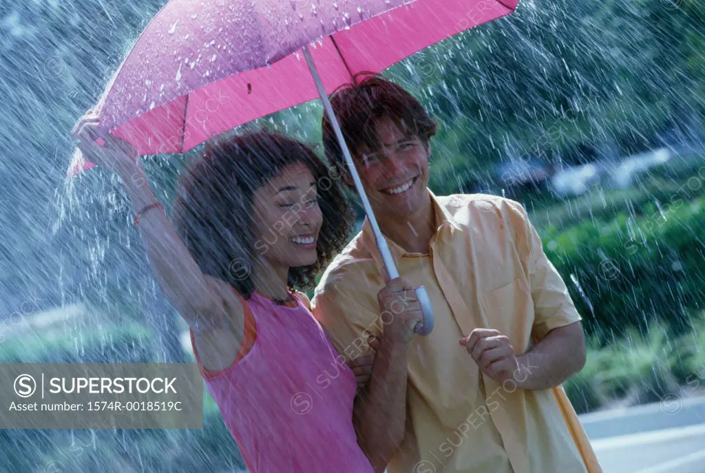 Young couple standing in the rain with an umbrella