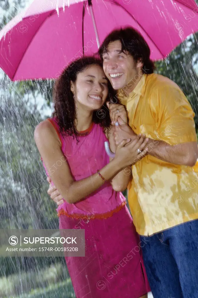 Young couple standing in the rain with an umbrella