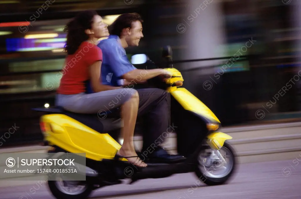 Side profile of a young couple riding a scooter