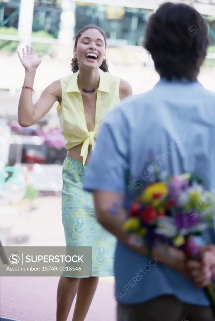 Rear view of a young man hiding a bouquet behind his back