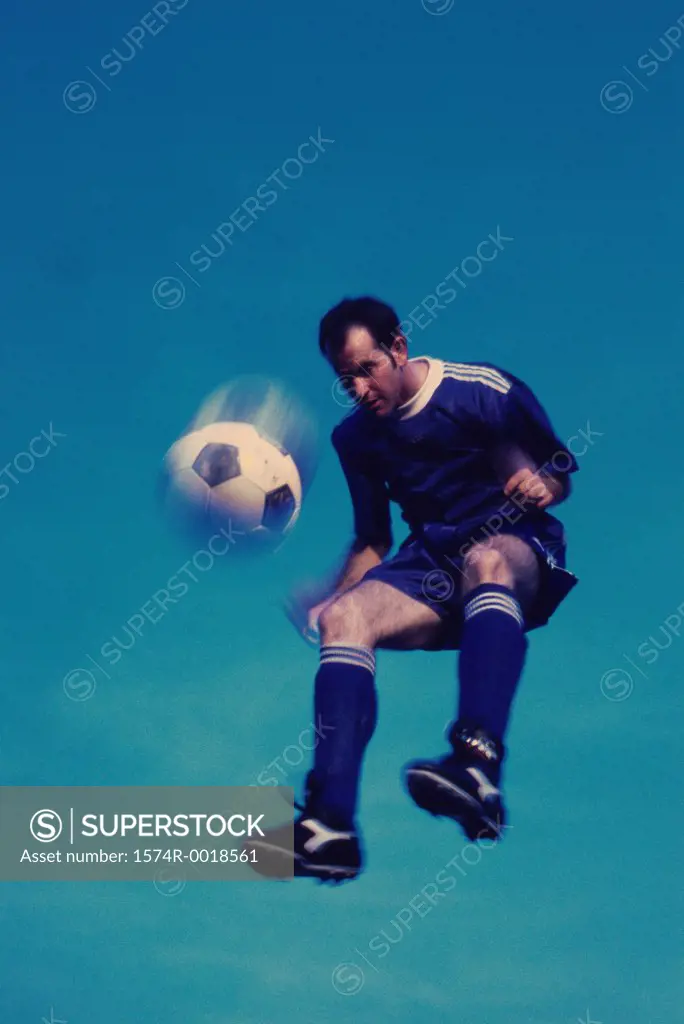 Low angle view of a soccer player in mid-air hitting a soccer ball