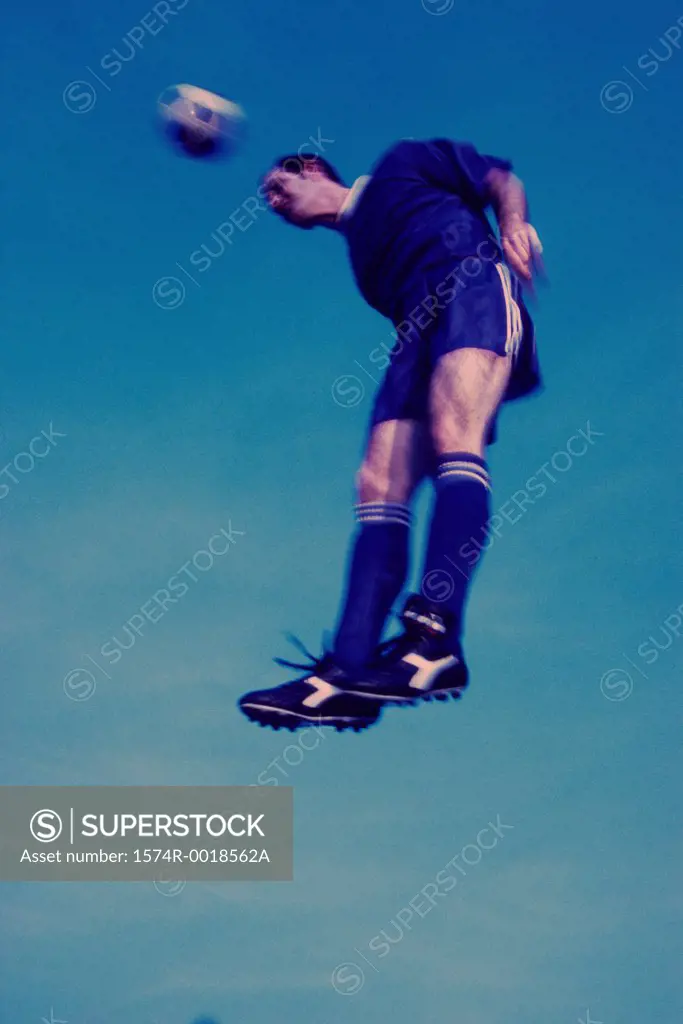 Low angle view of a soccer player in mid-air hitting a soccer ball with his head