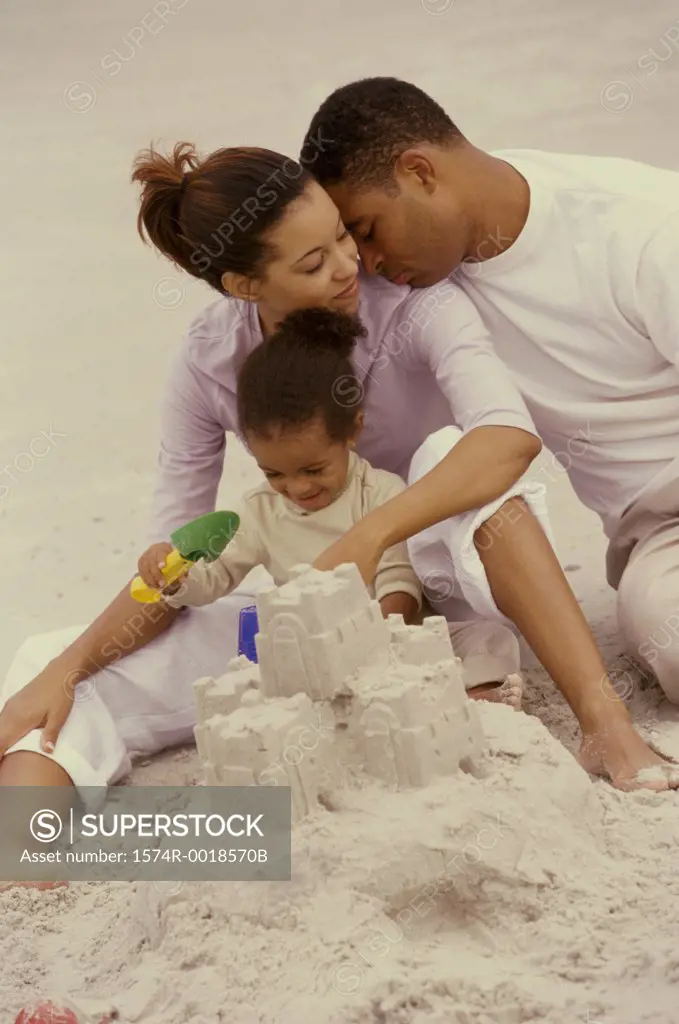 Parents making a sand castle with their daughter on the beach