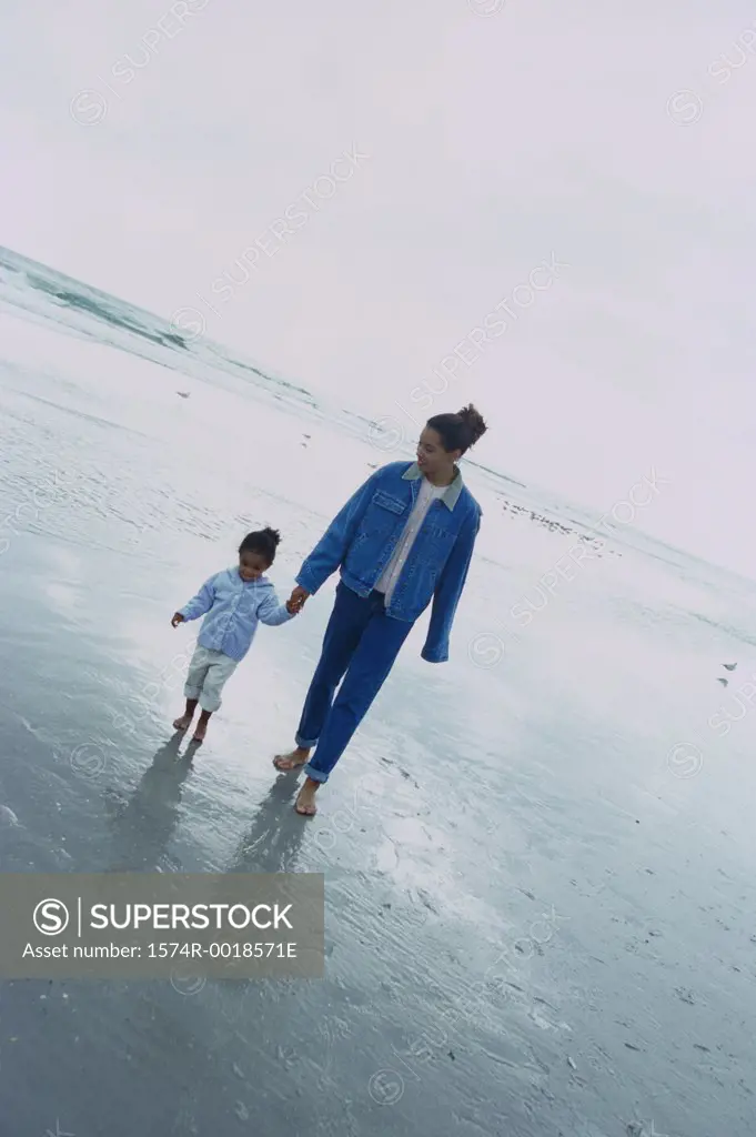 Young woman walking with her daughter on the beach