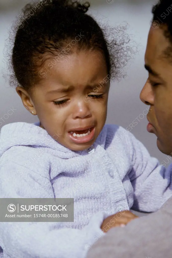Close-up of a daughter crying in her father's arms