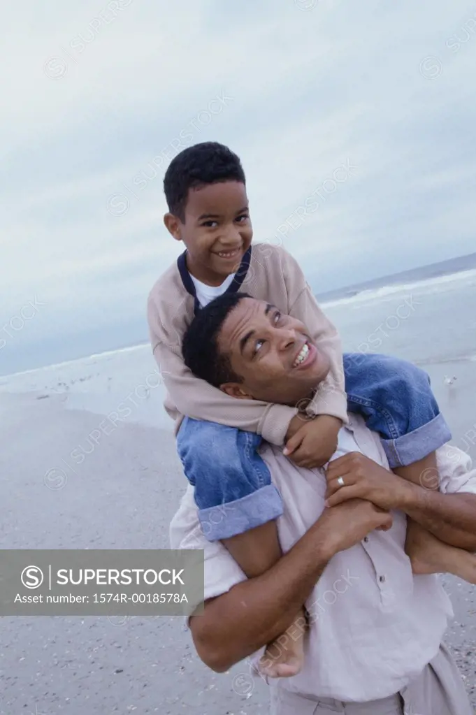 Close-up of a father carrying his son on his shoulders on the beach