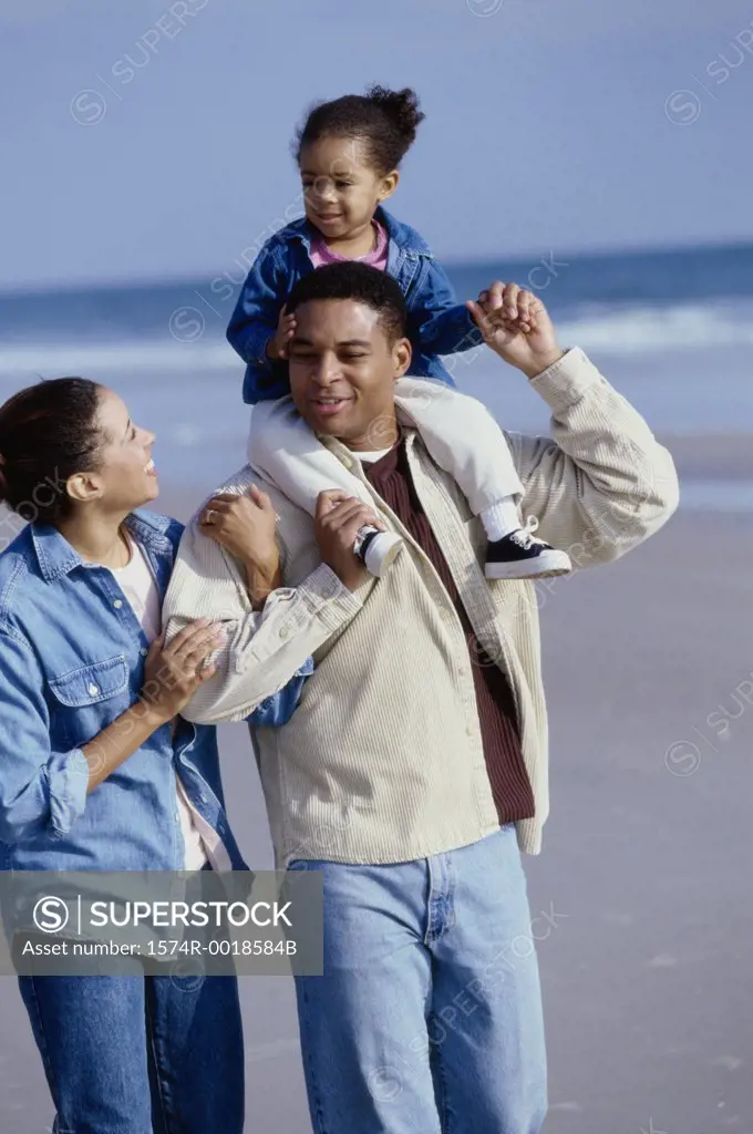 Parents smiling with their daughter on the beach
