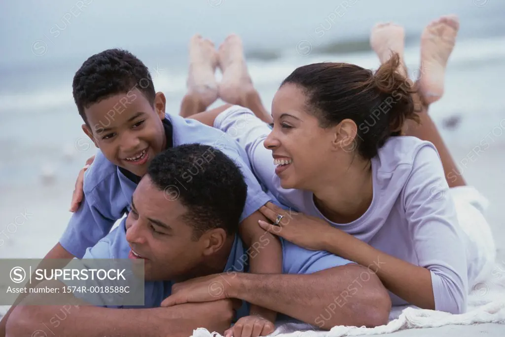 Close-up of parents smiling with their son on the beach