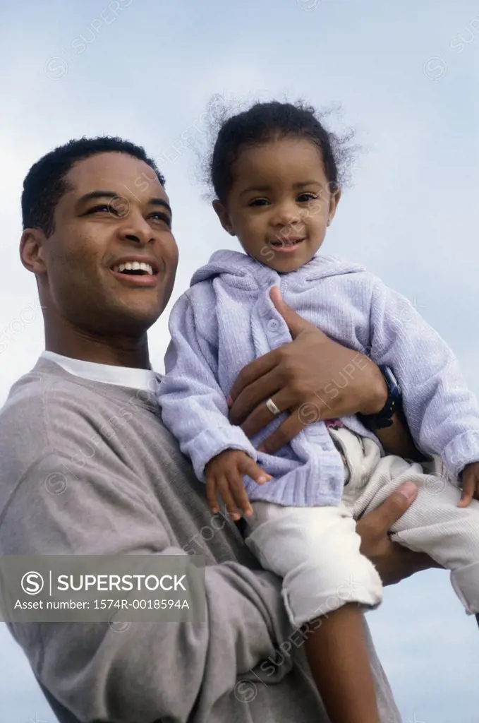 Close-up of a father carrying his daughter and smiling