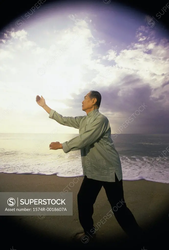 Side profile of a senior man practicing tai chi on the beach