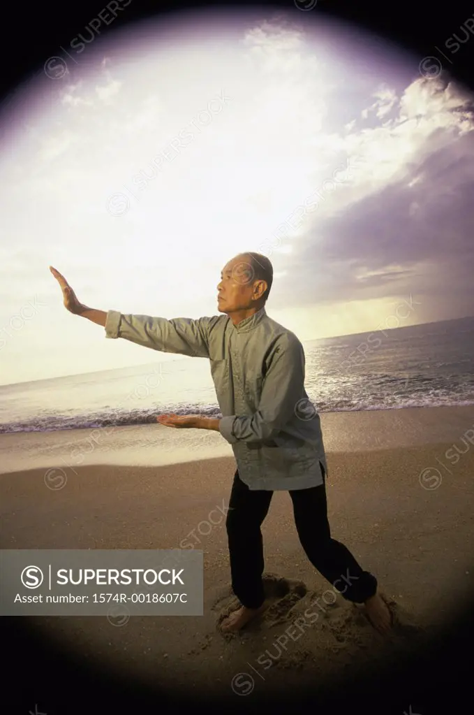 Side profile of a senior man practicing tai chi on the beach