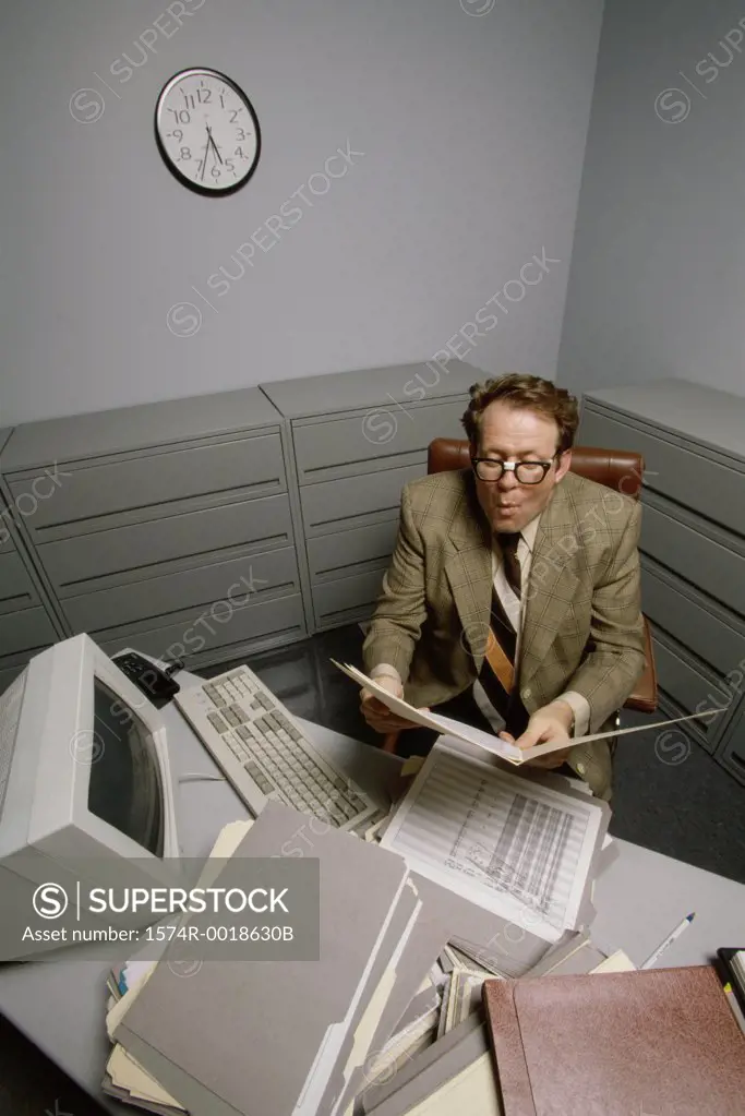 High angle view of a businessman reading a file sitting in an office