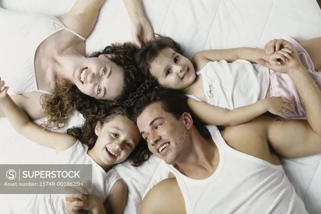 High angle view of parents lying on the bed with their two daughters