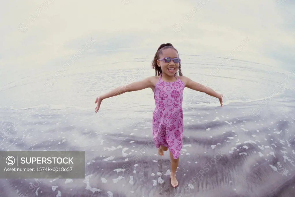 Close-up of a girl walking with her arms outstretched on the beach
