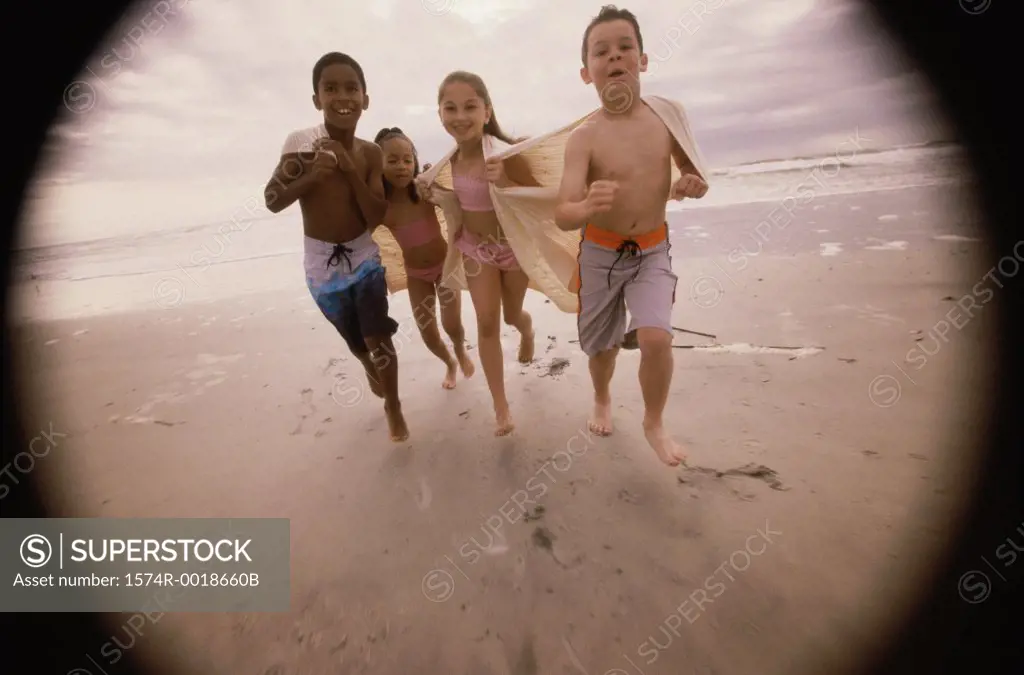 Portrait of two boys and two girls running on the beach