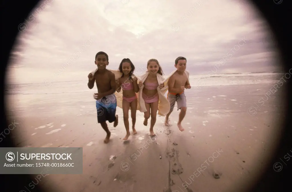 Portrait of two boys and two girls running on the beach