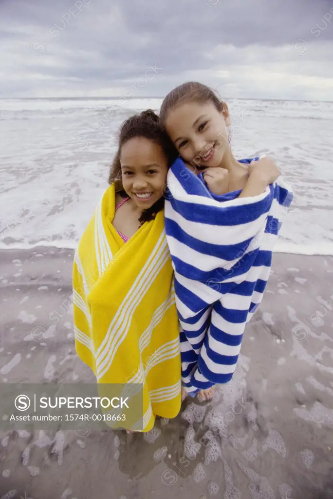 Portrait of two girls wrapped in towels on the beach