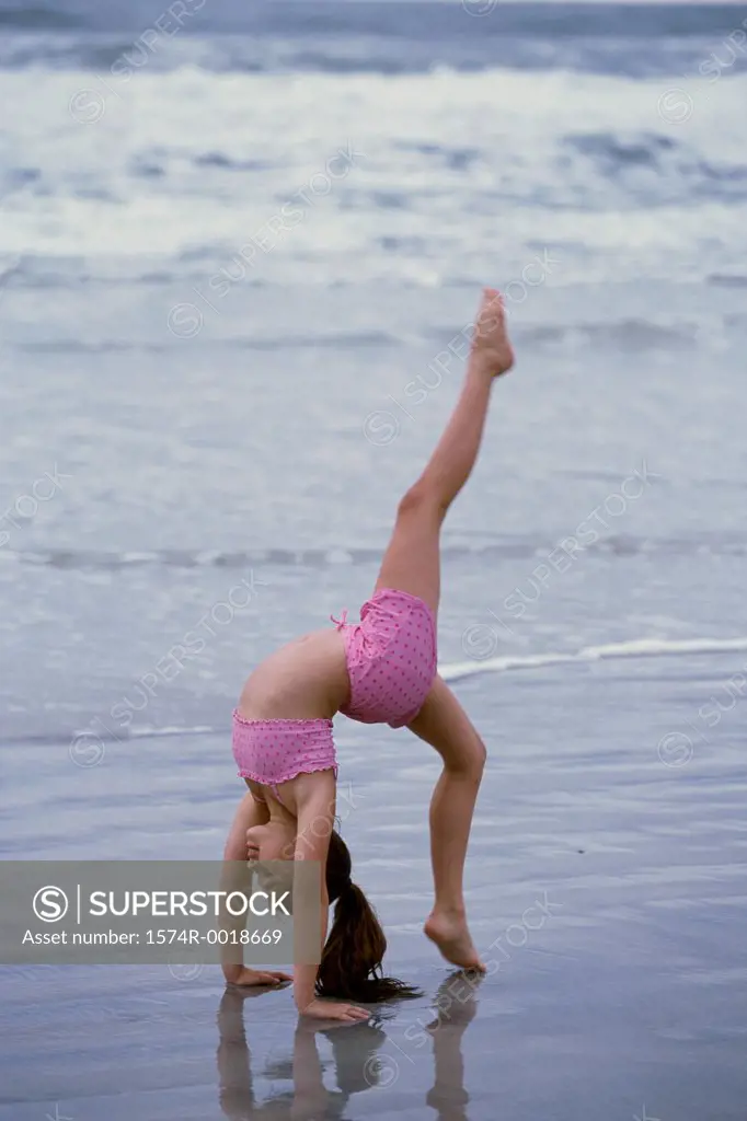 Side profile of a girl doing a cartwheel on the beach