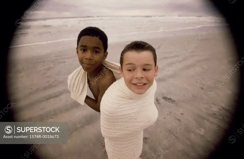 High angle view of two boys wrapped in a blanket on the beach