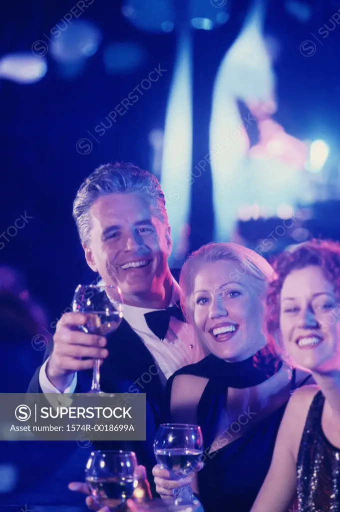 Portrait of two mature women and a mature man toasting with wineglasses