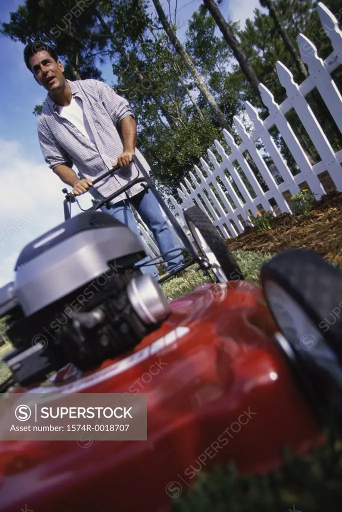Mid adult man pushing a lawn mower