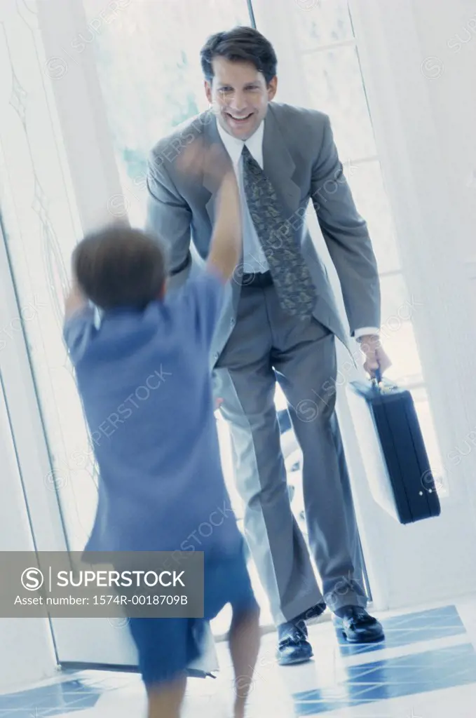 Boy running to greet his father at the front door