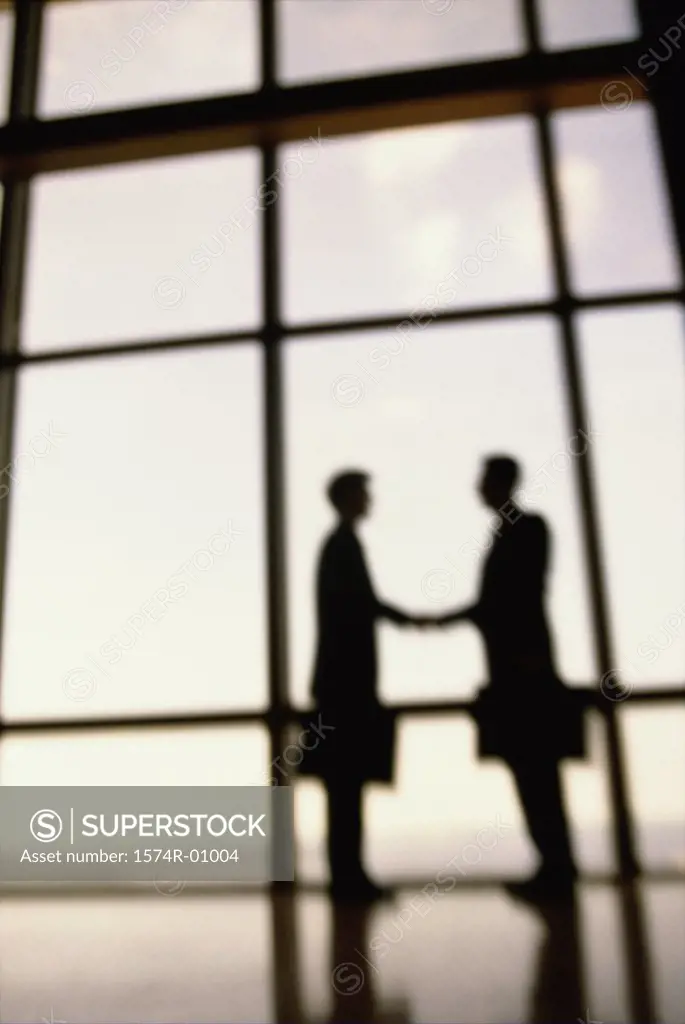 Silhouette of two businessmen shaking hands