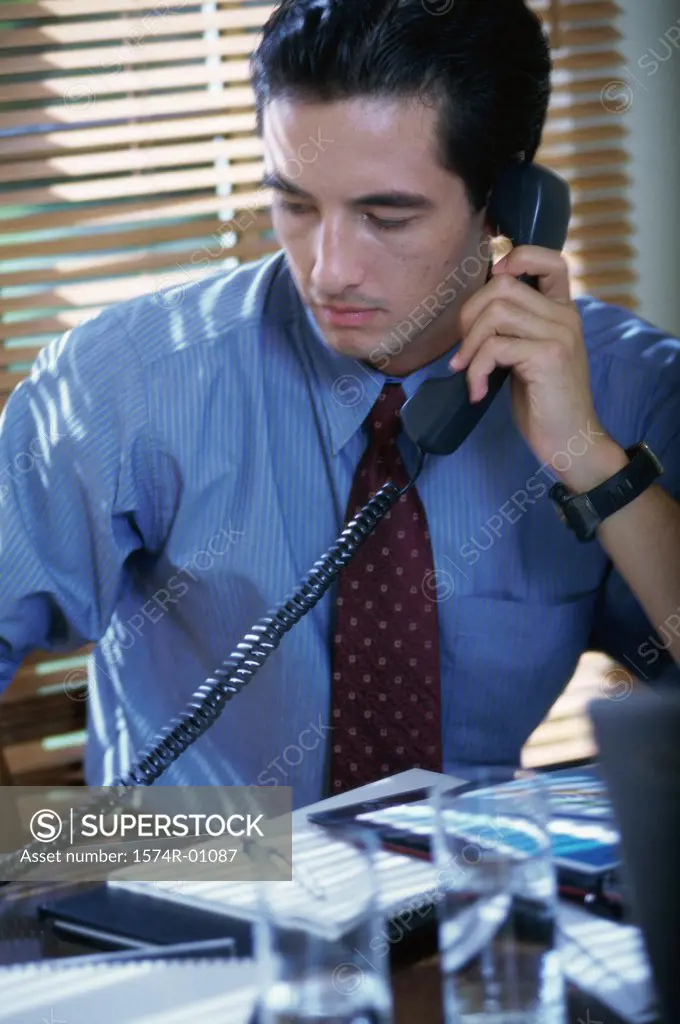 Close-up of a young businessman using the landline telephone at his desk