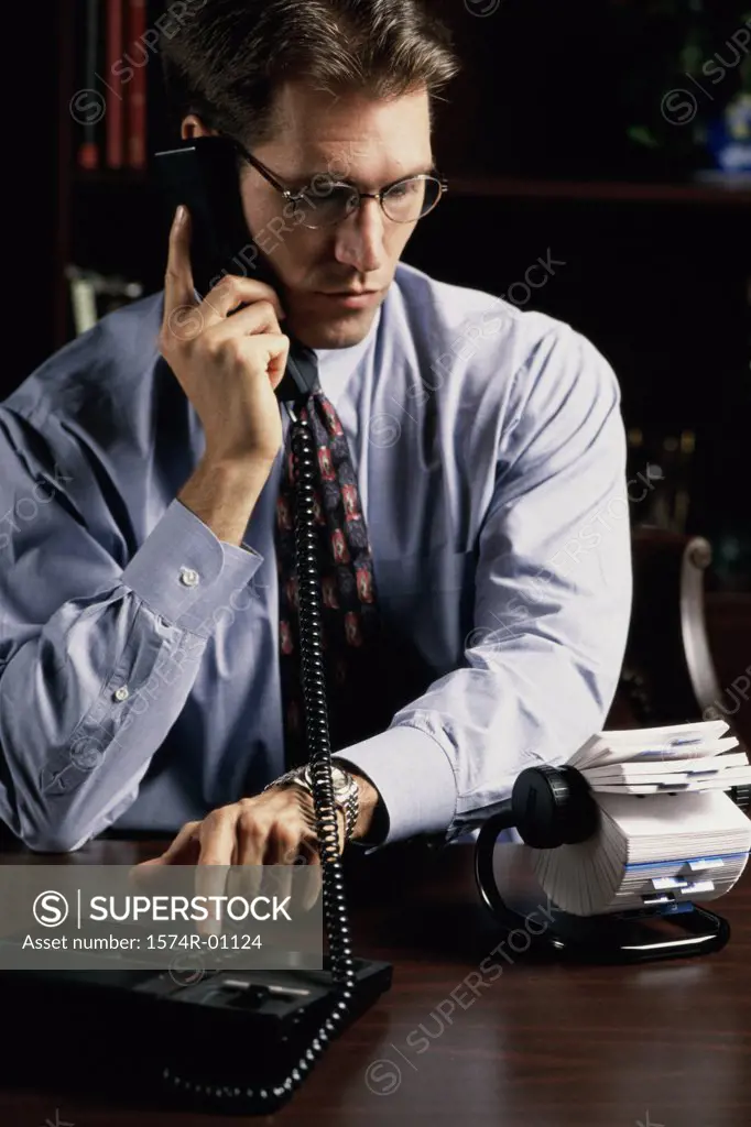 Young businessman using a landline telephone on his desk