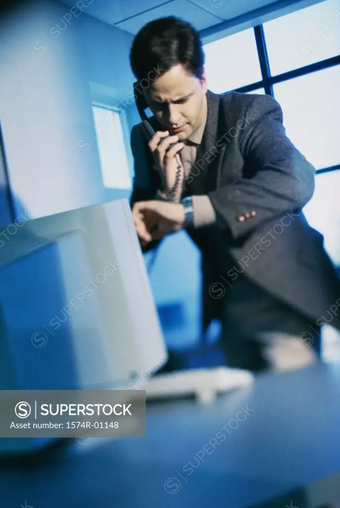 Young businessman using a landline telephone on his desk