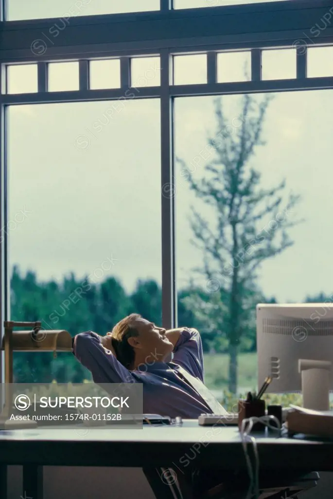 Businessman sitting in an office looking out of a window