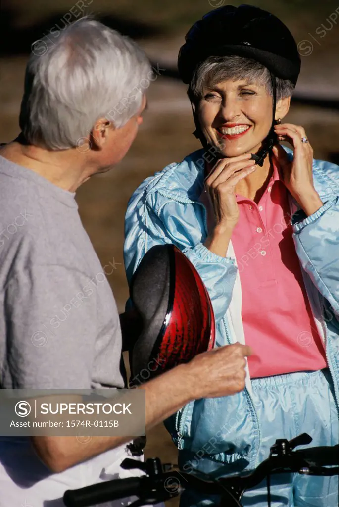 Woman putting on a cycling helmet standing with a man