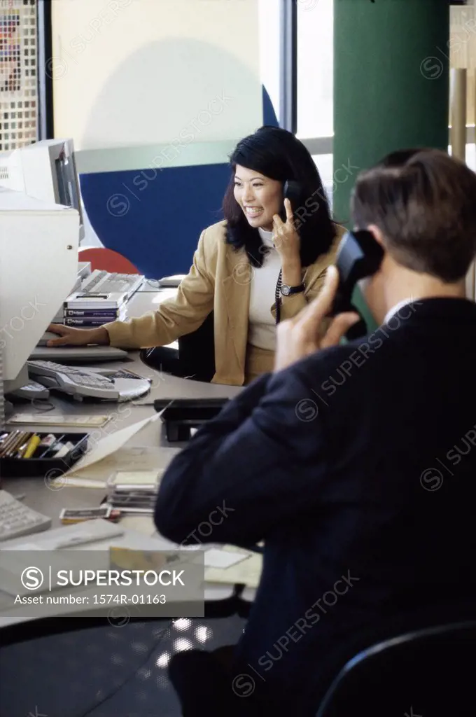 Two business executives talking on the landline telephone in the office