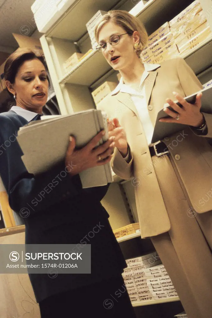 Low angle view of two businesswomen looking at files in a supply room