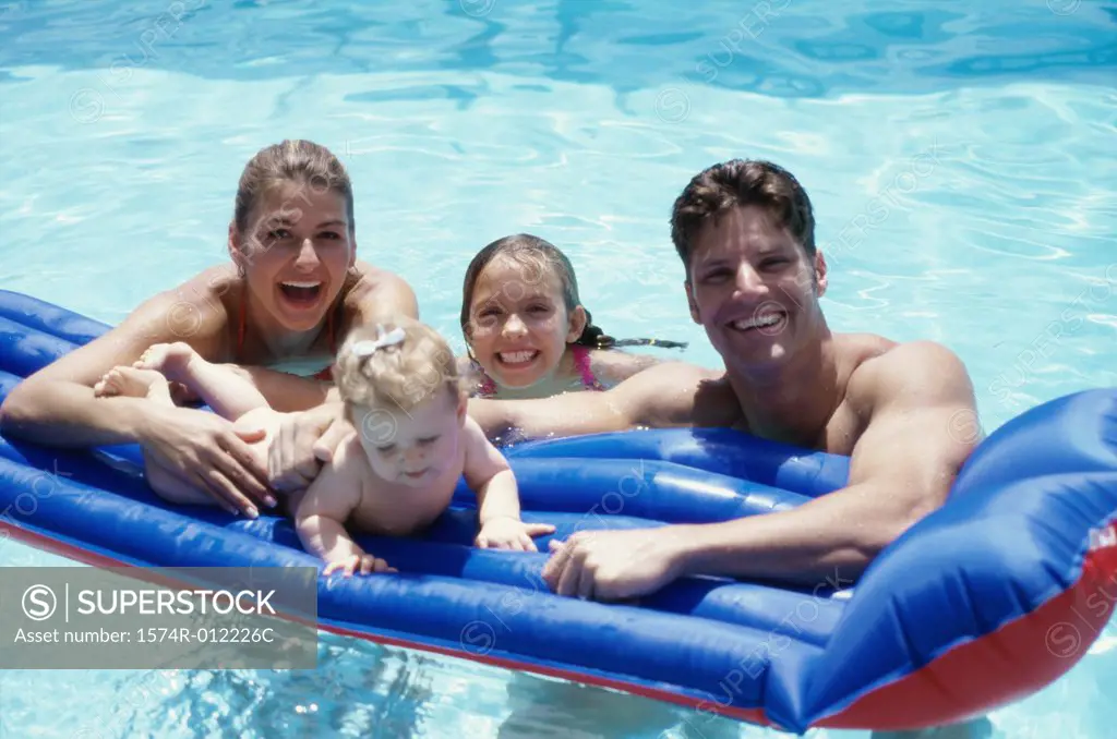 Portrait of parents with their two daughters on a pool raft in a swimming pool