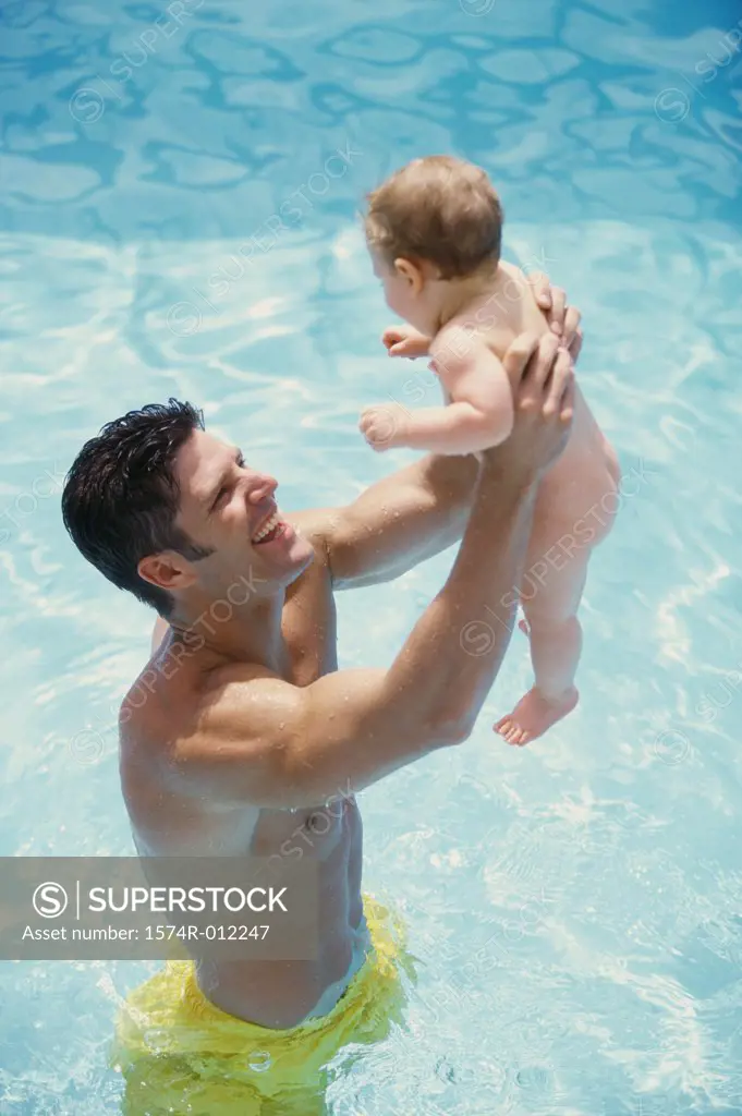 High angle view of a father holding up his baby boy in a swimming pool