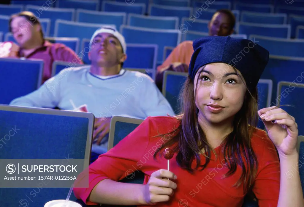 Close-up of a teenage girl sitting in a movie theater with a lollipop