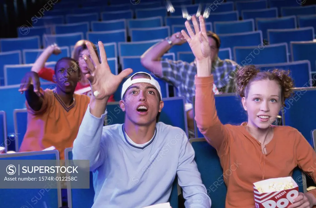 Five teenagers sitting in a movie theater throwing popcorns