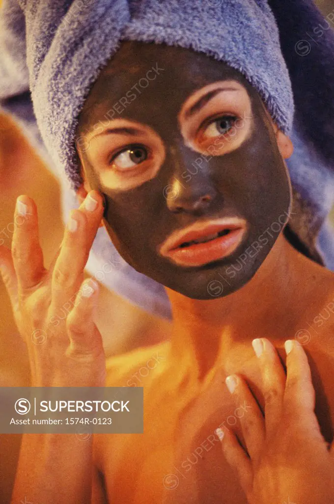 Close-up of a young woman applying a facial mask with her finger