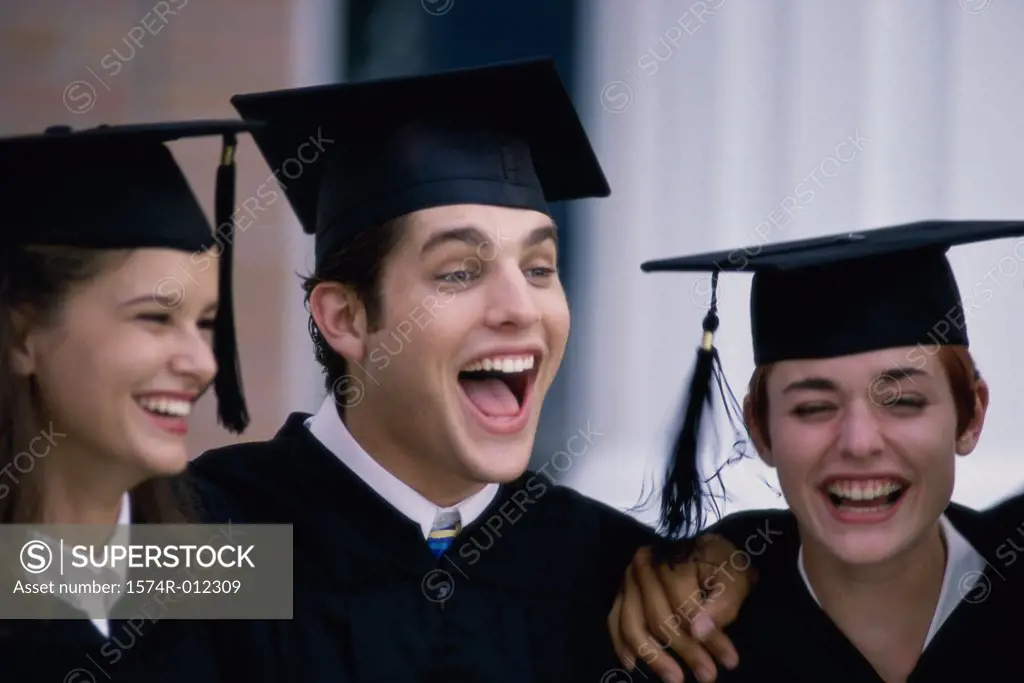 Close-up of a three young graduates laughing