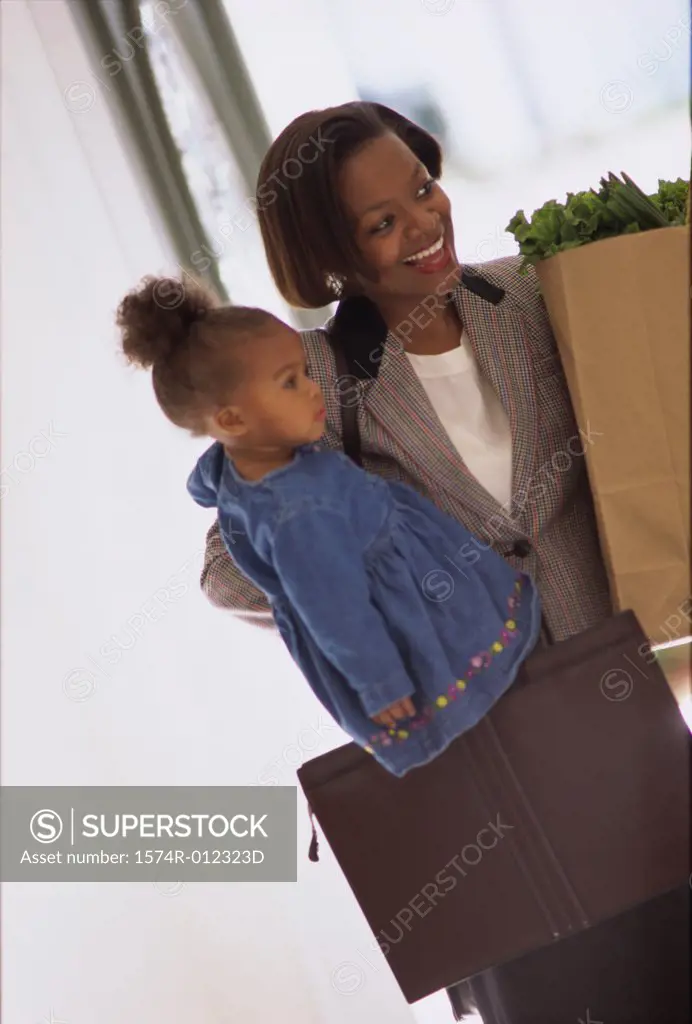Mother carrying her daughter and holding shopping bags