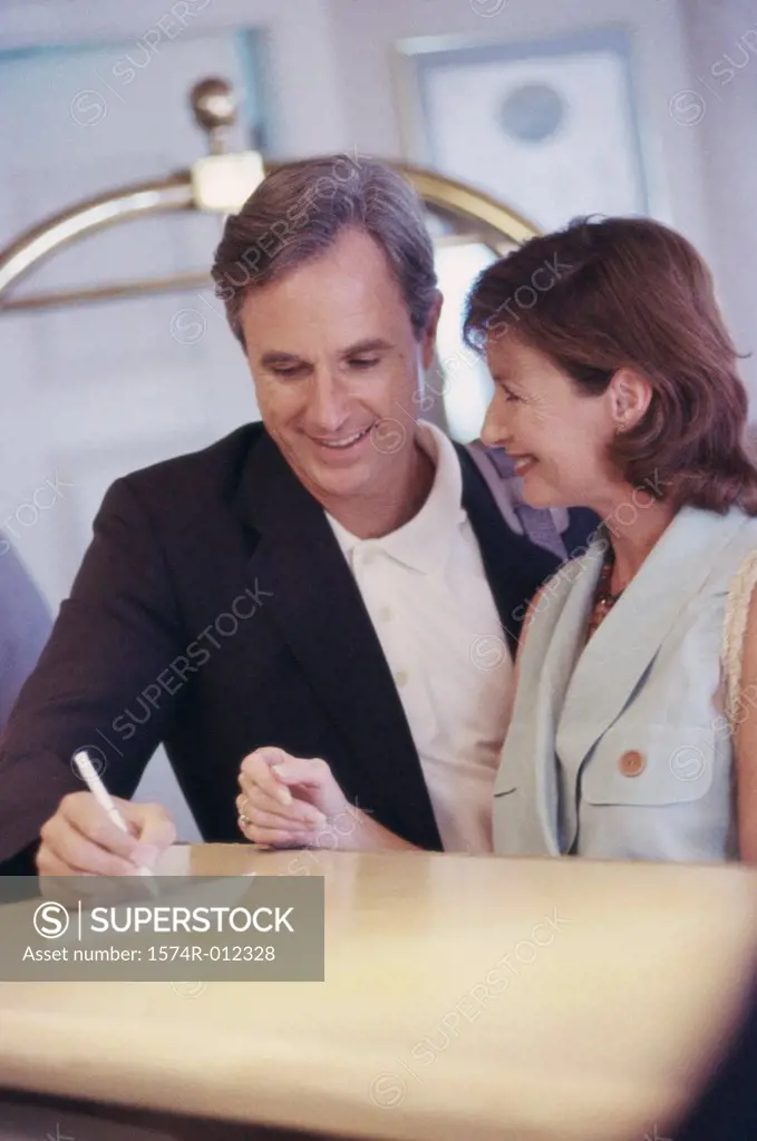 Mid adult couple checking in at a hotel reception desk